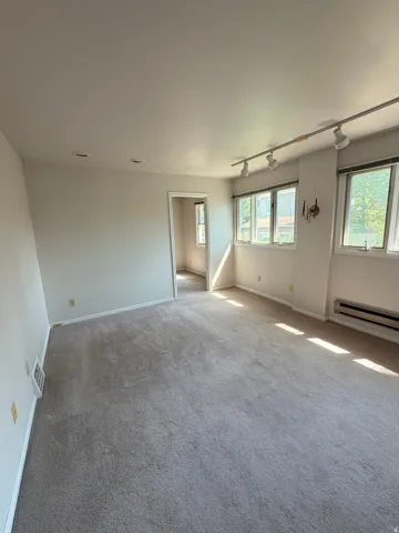 Expansive room with neutral carpet, multiple windows, and recessed lighting