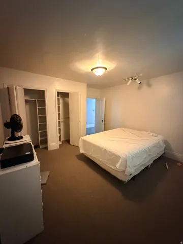Spacious primary bedroom featuring neutral carpeting, dual reach-in closets with sliding doors, and recessed ceiling lighting