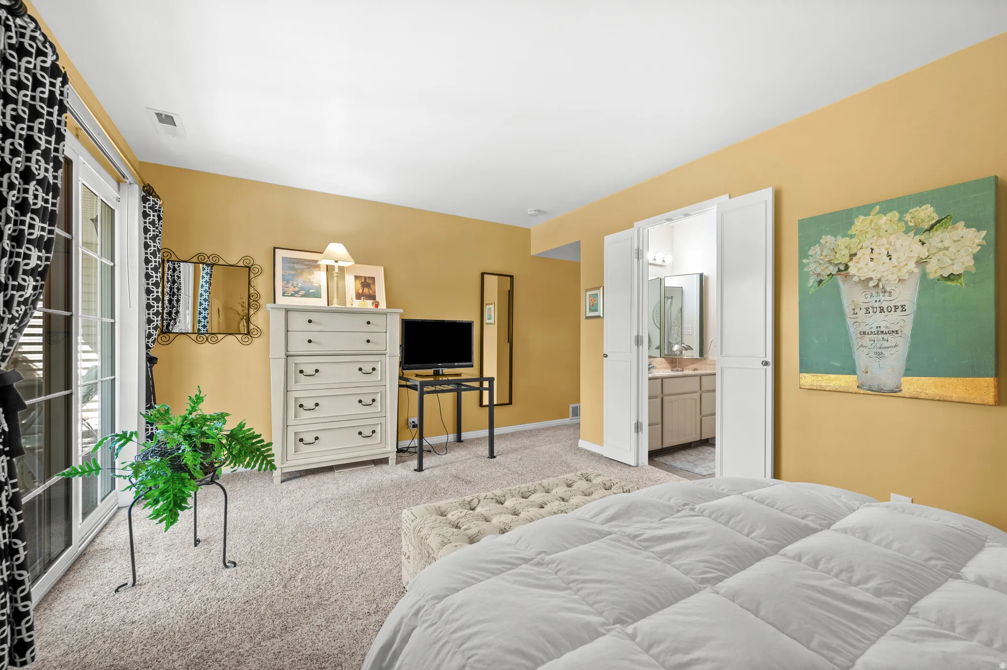 Sliding glass patio door with privacy blinds, soft carpet flooring, and an integrated en-suite bathroom with vanity