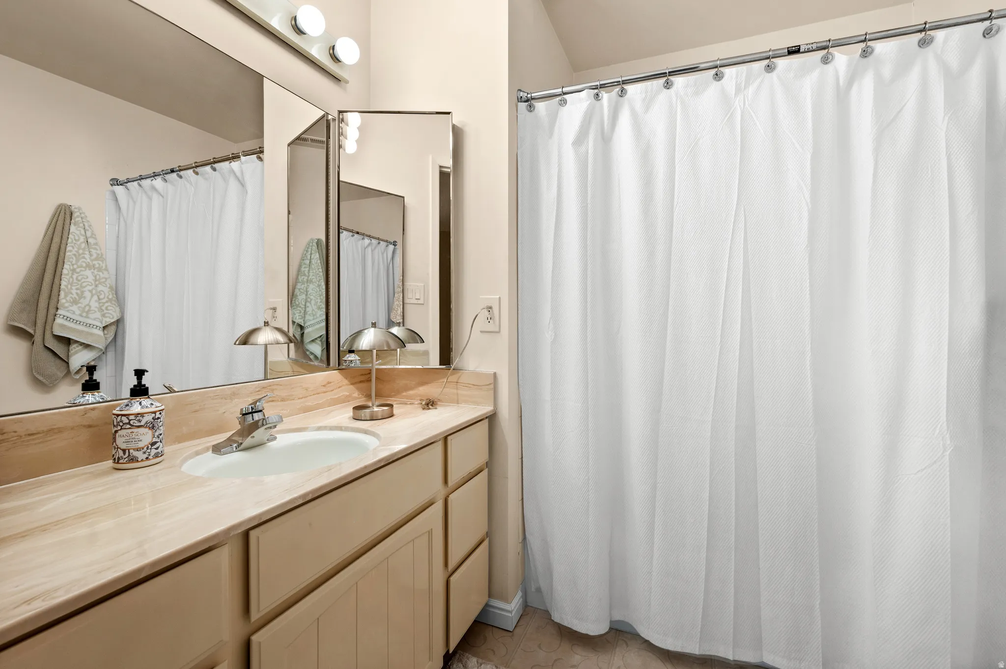 Vanity with a light-toned countertop, undermount sink, and chrome faucet