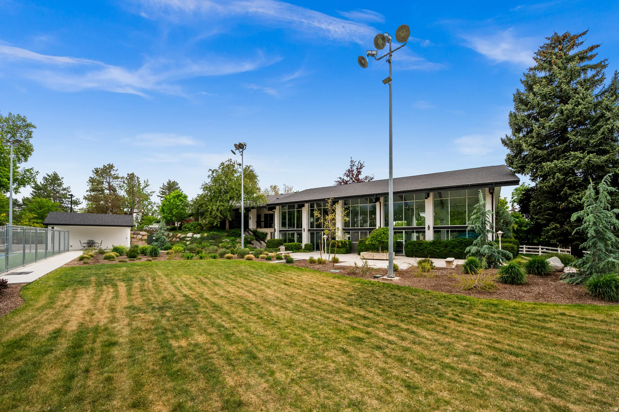 Expansive exterior featuring a wide lawn, extensive landscaping, and a tennis court