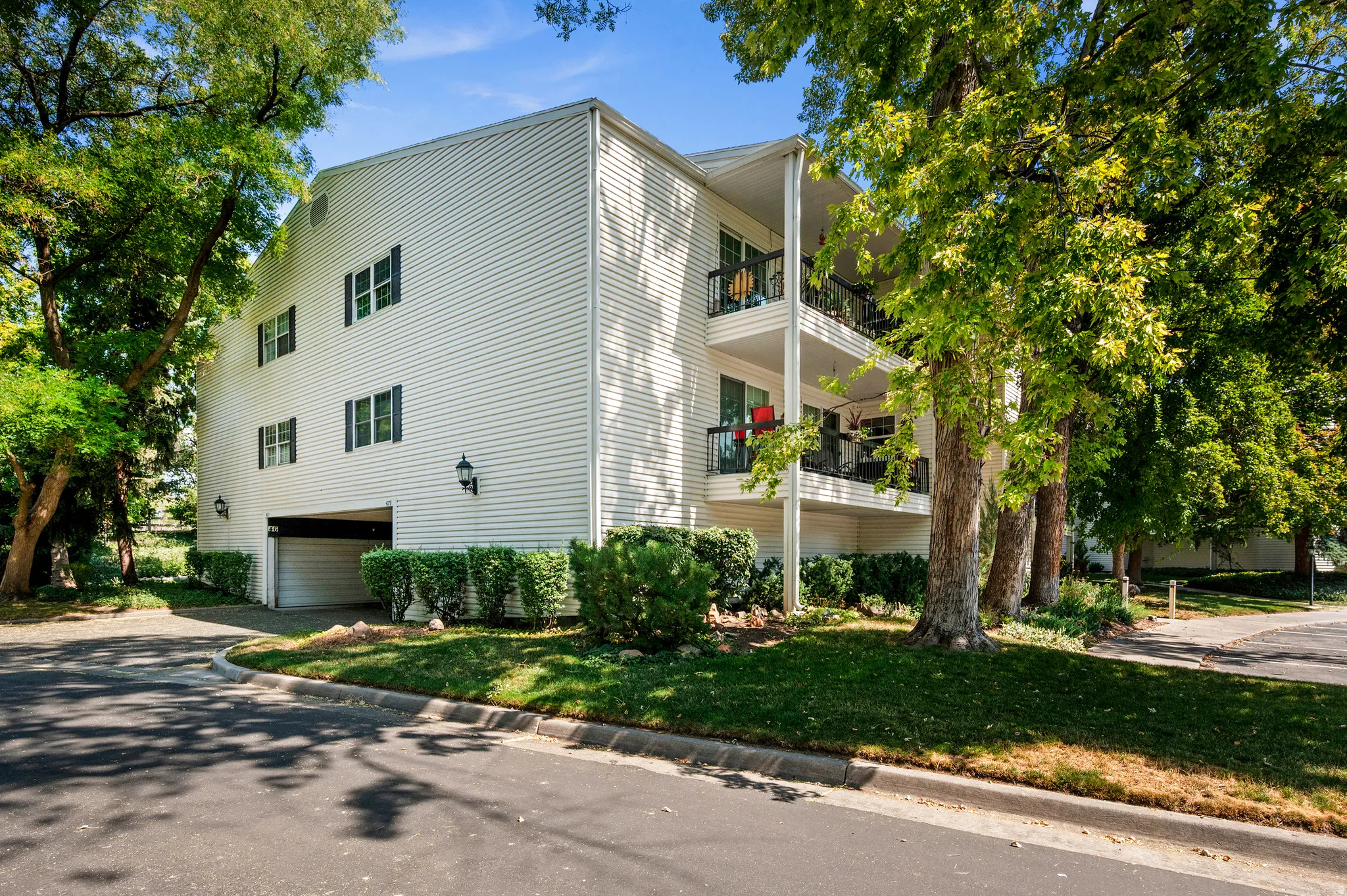 Multi-level building with white siding, multiple balconies, and a ground-level garage