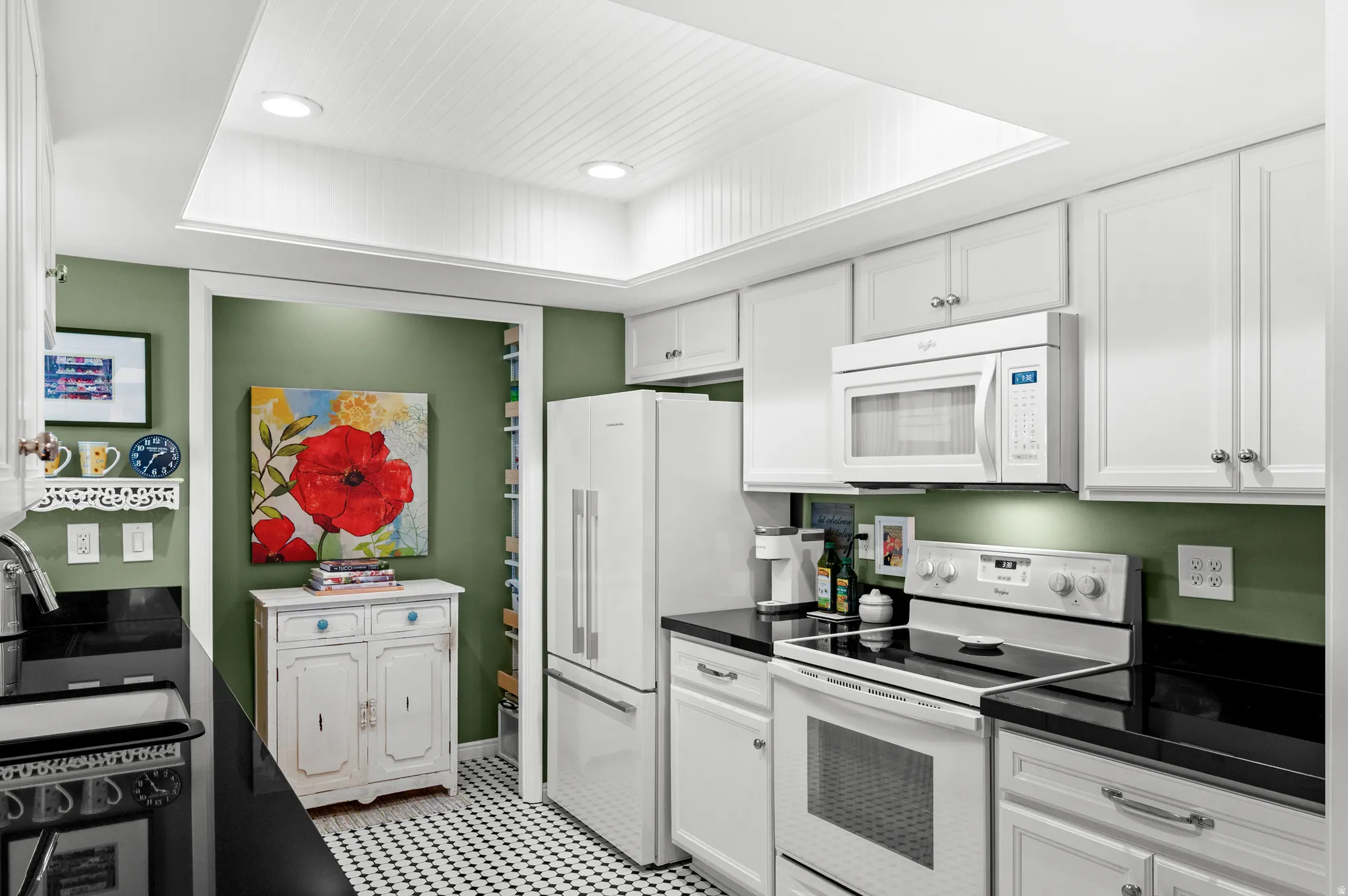 Kitchen featuring white cabinetry, black countertops, white appliances, and a black and white checkerboard tile floor