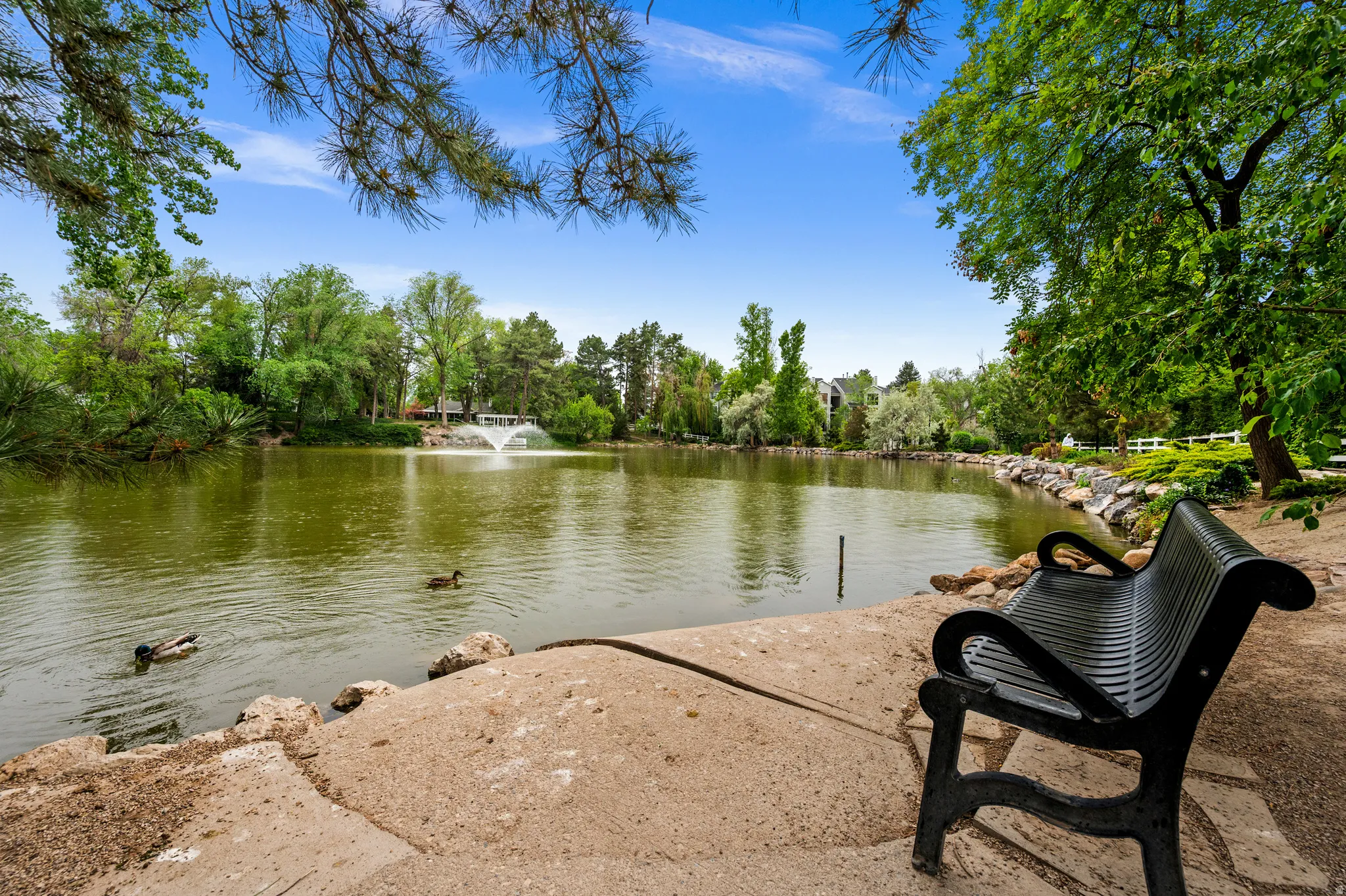 Waterfront property with a fountain feature, mature trees, and a dedicated seating area