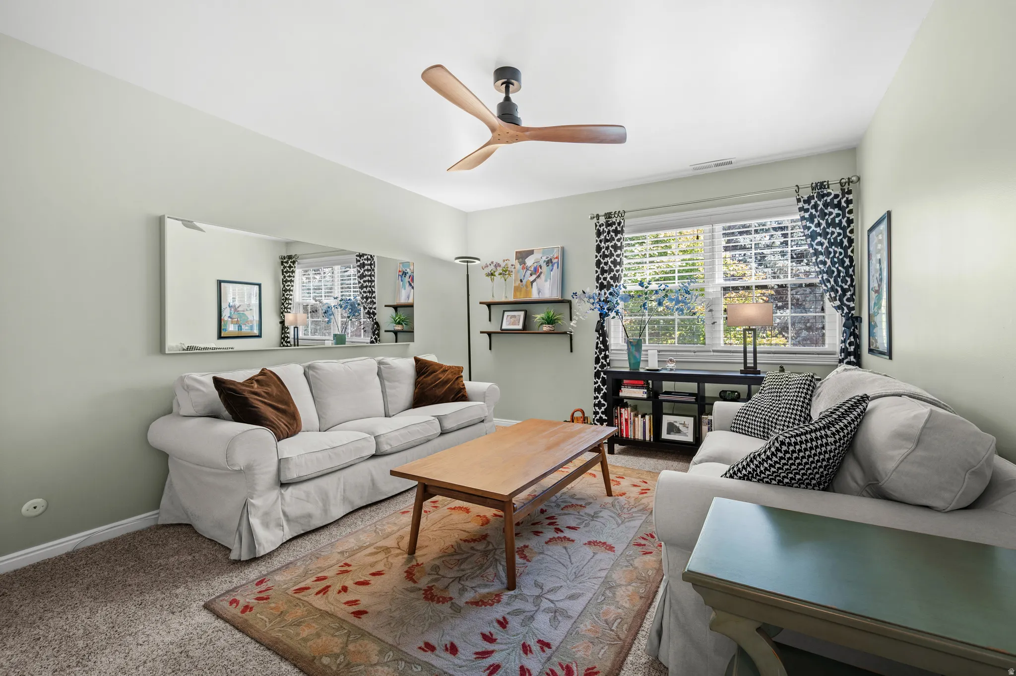 Recessed lighting with a ceiling fan, dual windows with blinds, wall-mounted shelving, and carpeted flooring