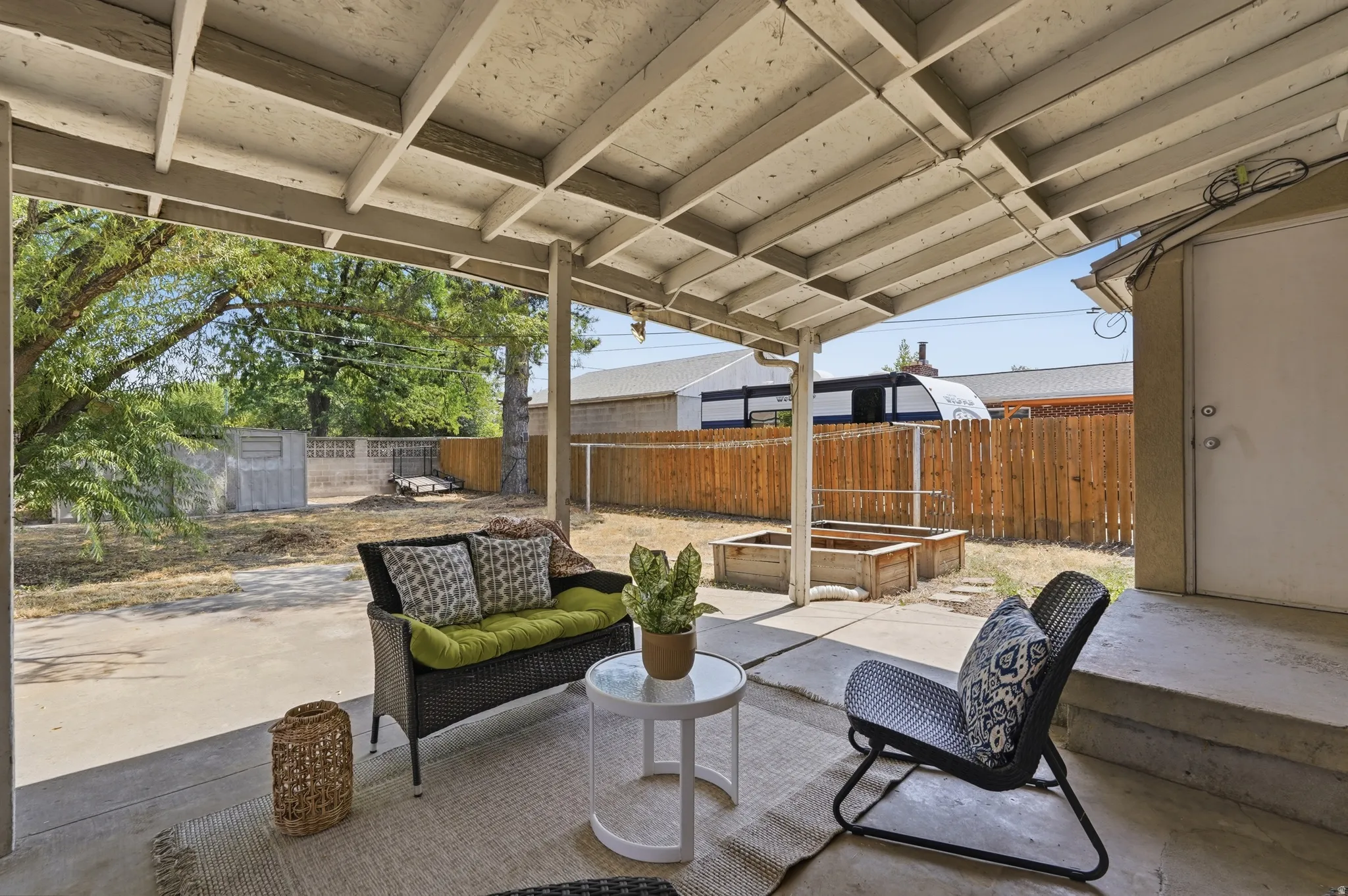 Covered patio with polished concrete flooring and steel beam structure, featuring integrated seating with built-in cushioned bench