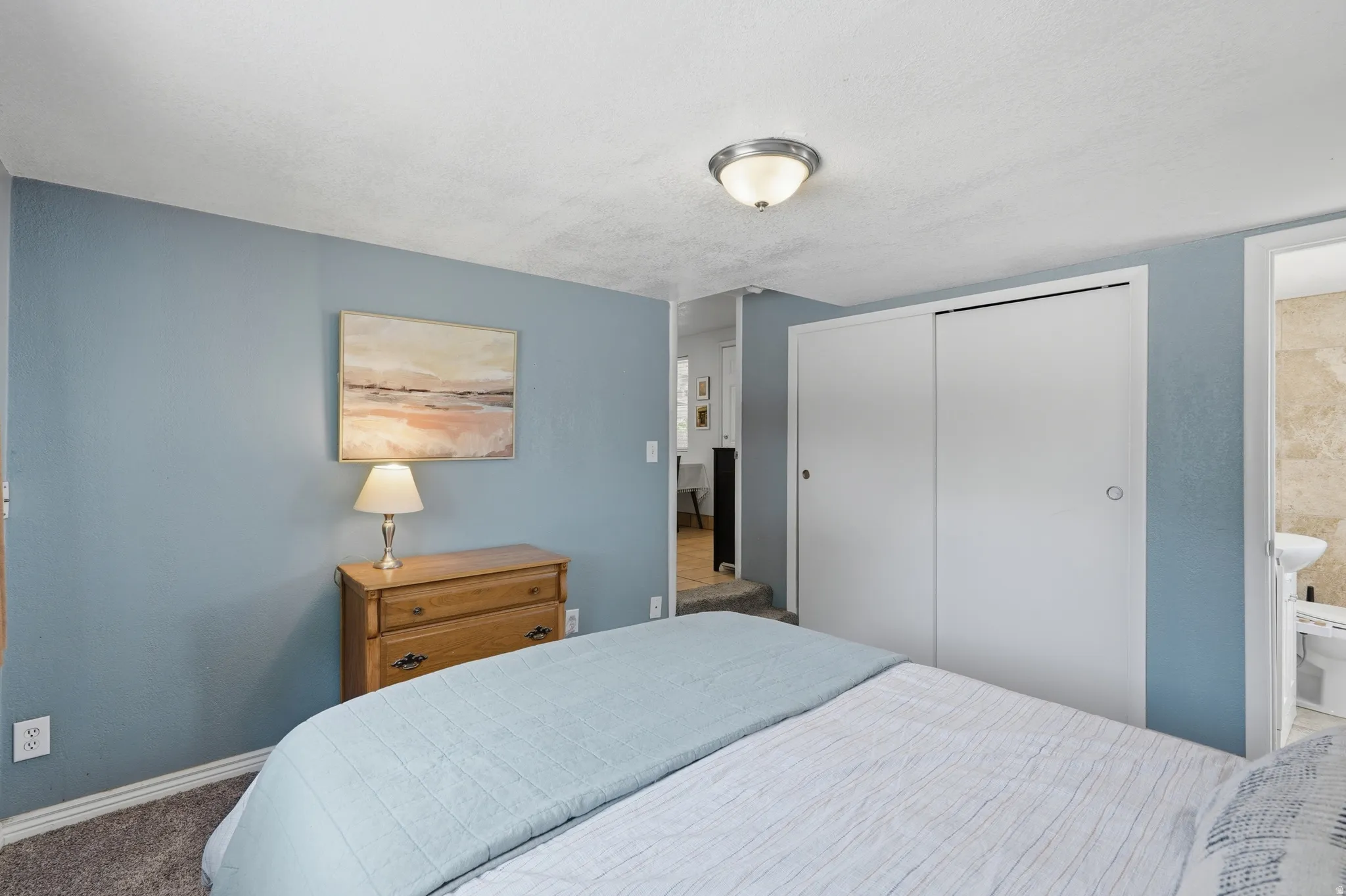 Recessed lighting fixture, textured ceiling, sliding closet doors, carpeted flooring, and light blue wall finish