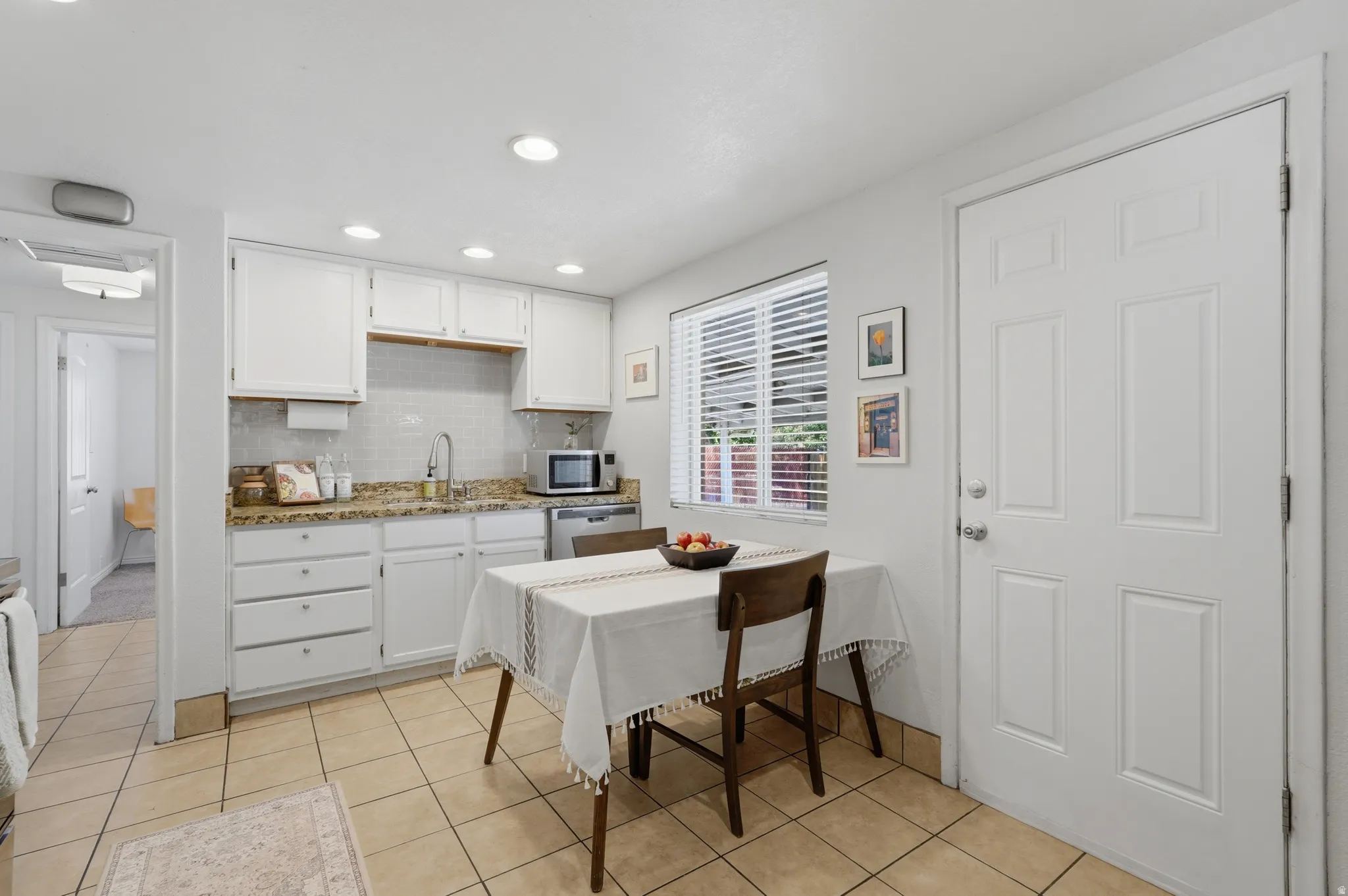 Kitchen featuring white cabinetry, granite countertops, tile flooring, and a stainless steel sink