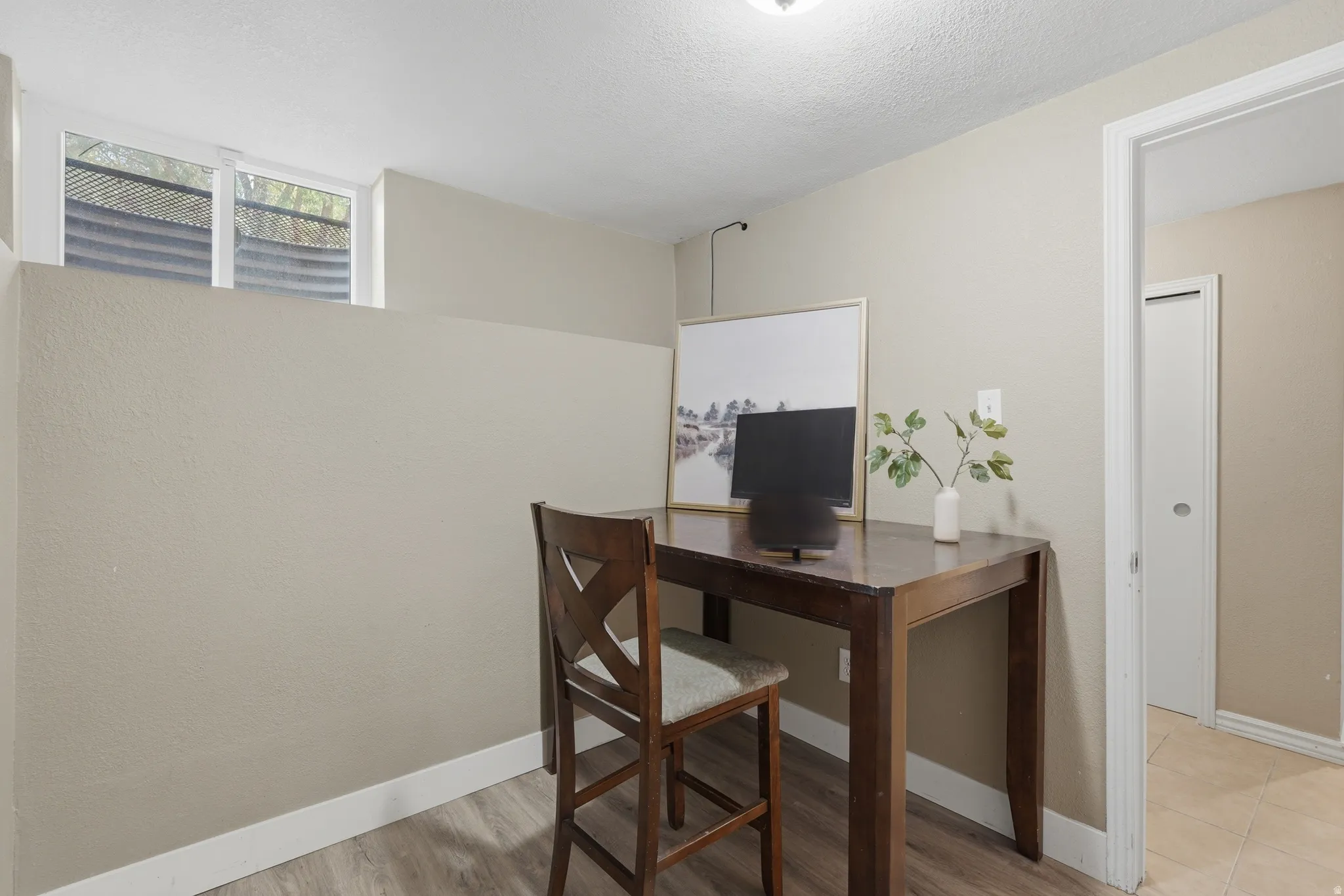 Dedicated home office featuring a wood-finish desk, X-back chair, and ample natural light from transom windows