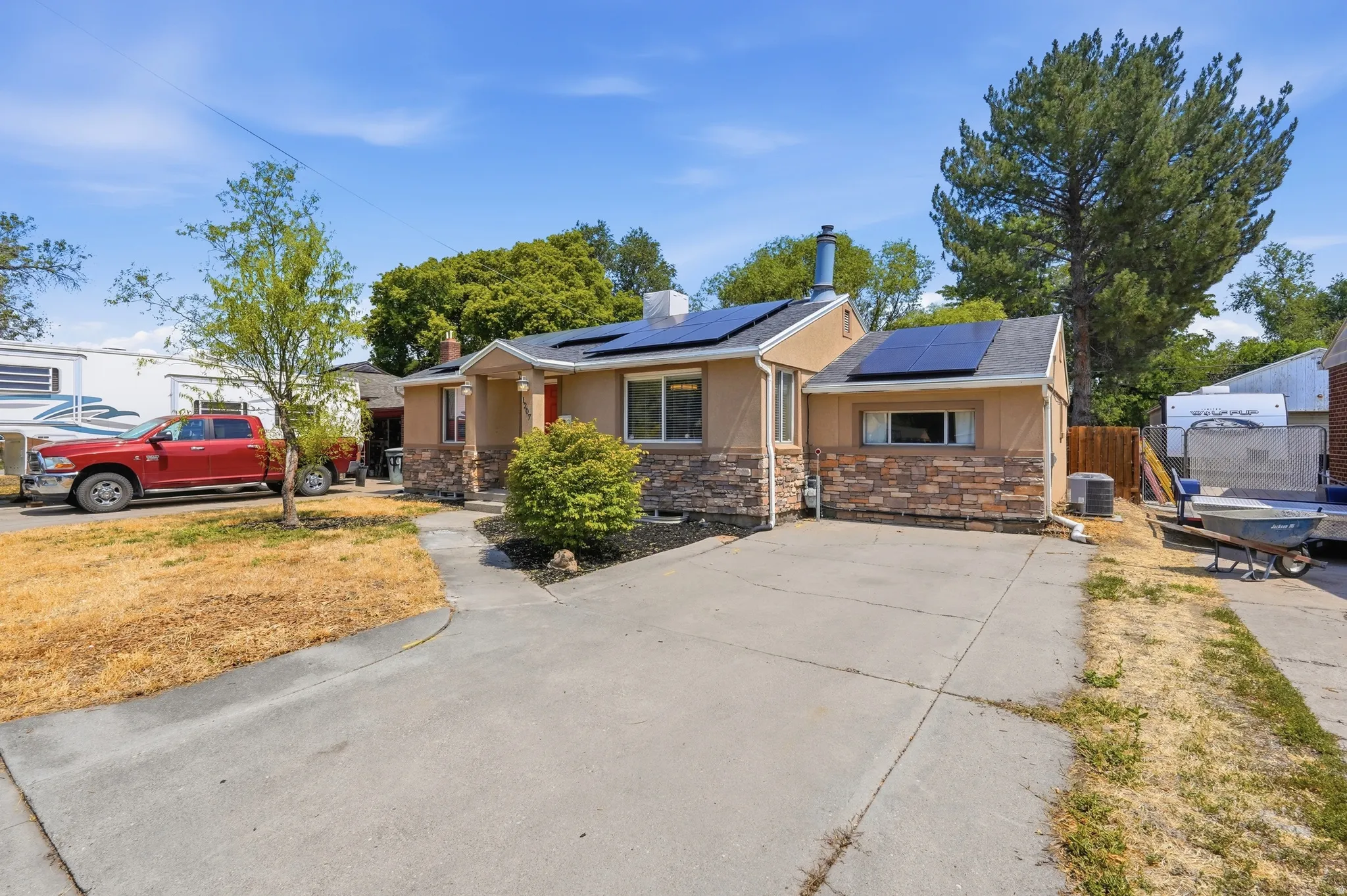 Charming brick residence featuring a concrete driveway, attached garage, and mature landscaping with established trees and shrubs