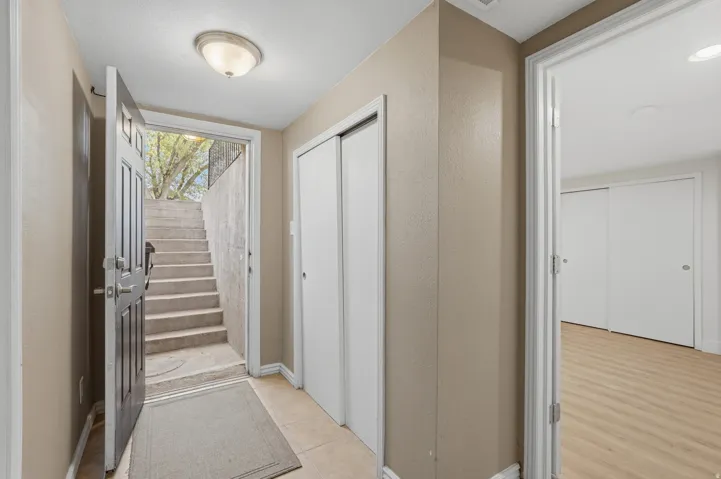 Bright hallway featuring neutral wall finishes, recessed ceiling lighting, wood-finish flooring, and multiple white panel doors providing access to adjoining spaces
