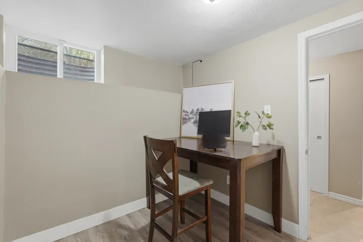 Dedicated home office featuring a wood-finish desk, X-back chair, and ample natural light from transom windows