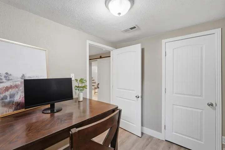 Light wood-finish flooring, white paneled doors, and a flush mount ceiling light