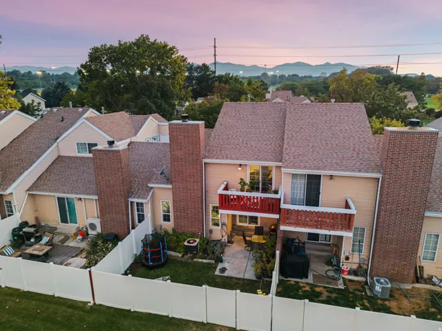 Private fenced yard with patio, upper balcony, and brick chimney structures