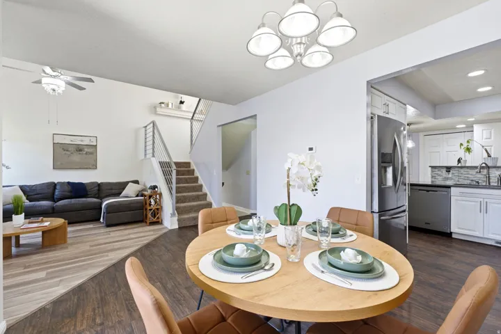 Open-concept living space featuring wood-finish flooring, a contemporary chandelier, and stainless steel kitchen appliances