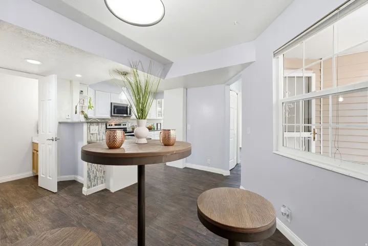 Wood-finish flooring throughout, kitchen with white cabinetry, stainless steel microwave, and tile backsplash