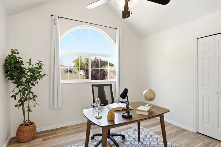 Vaulted ceiling with a ceiling fan, arched window with white trim, light wood-finish flooring, and a bi-fold closet door
