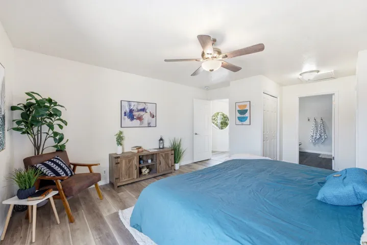 Wood-finish flooring, ceiling fan with integrated lighting, built-in closet with bifold doors, and a decorative circular window