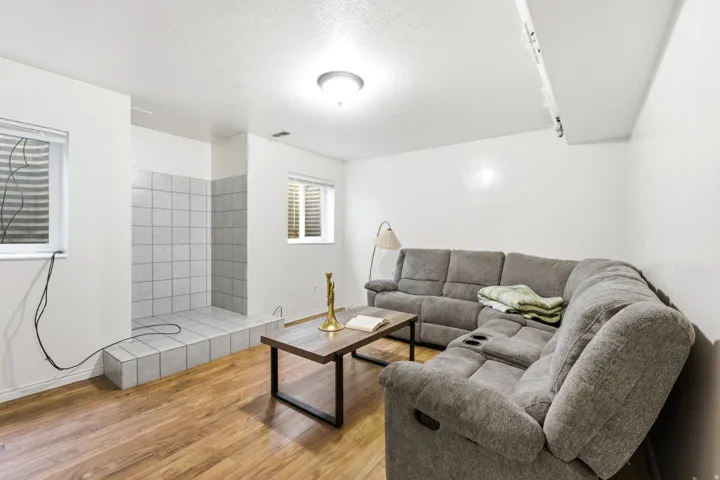 Finished basement featuring a spacious recreation area with plush seating, wood-finish flooring, and recessed lighting