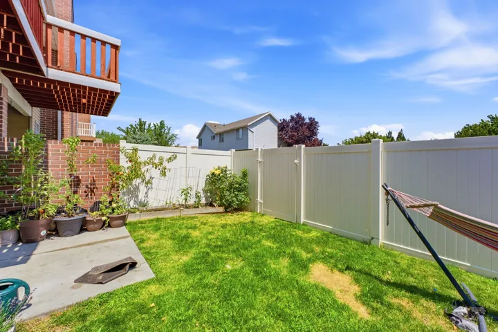 Enclosed backyard featuring a concrete patio, grassy area, and tall privacy fencing