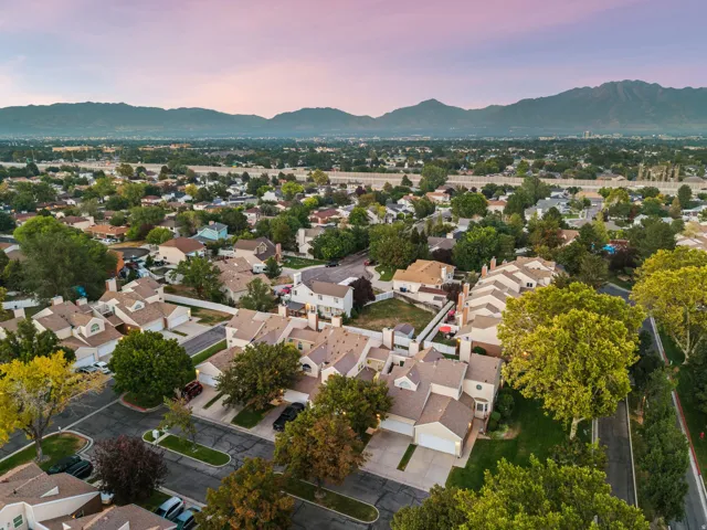 Residential neighborhood with a mountain backdrop, mature trees, and a mix of single-family homes and townhomes