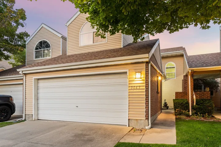 Exterior siding, arched windows, attached garage, brick accents, and a covered entry