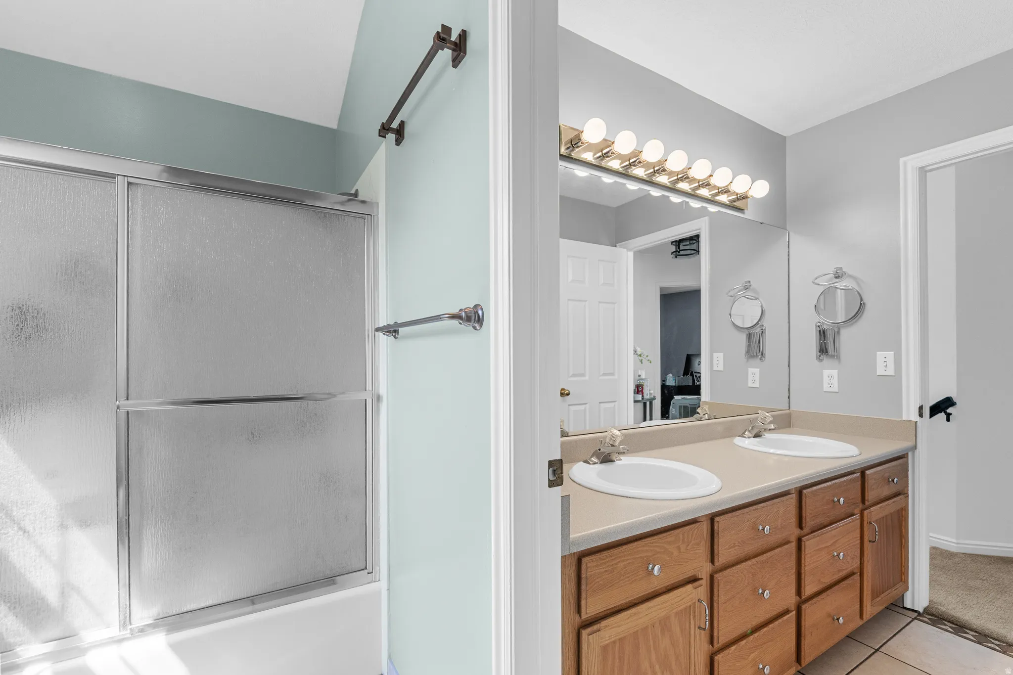 Dual vanity with integrated sinks, wood-finish cabinetry, and full-width mirror
