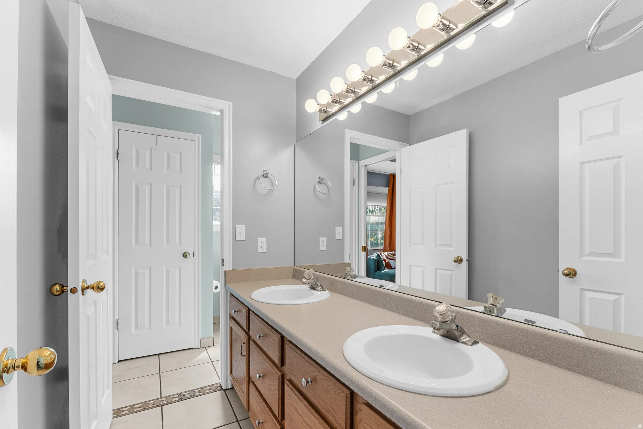 Dual vanity with integrated sinks, wood-finish cabinetry, and a full-width mirror