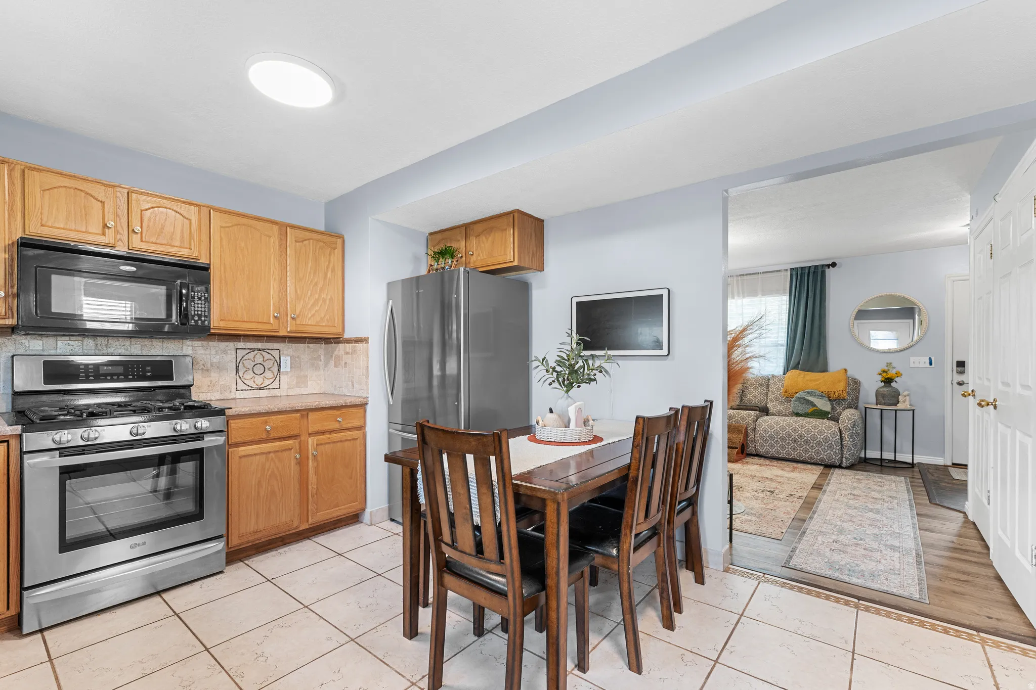 Kitchen with wood cabinetry, stainless steel appliances, tile flooring, and recessed lighting