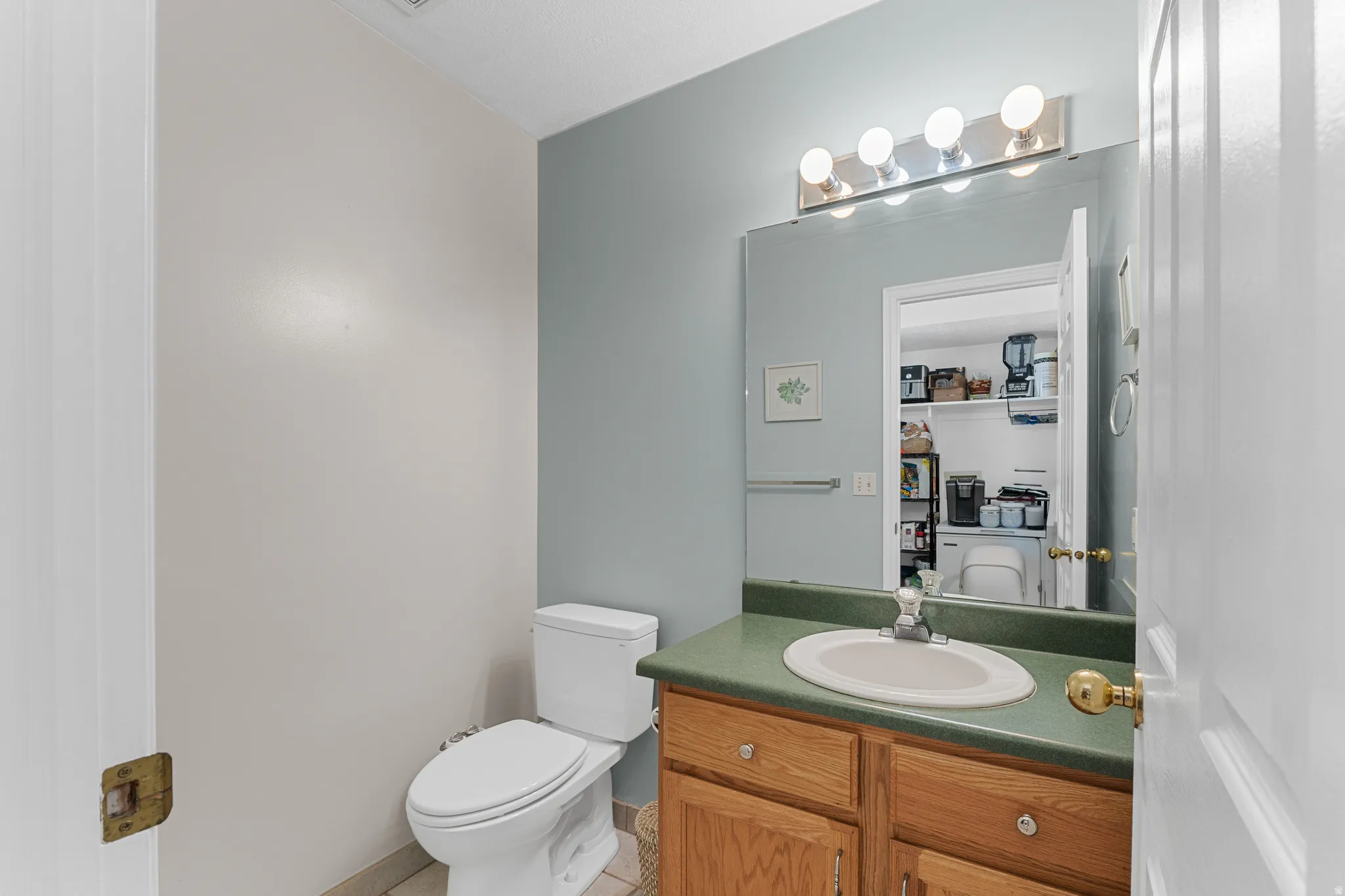 Wood-finish vanity with an integrated sink, green countertop, and polished chrome faucet