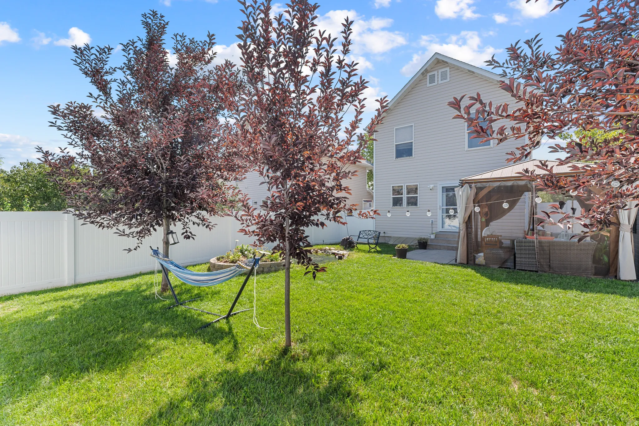 Expansive backyard with a manicured lawn, established trees, and a privacy fence