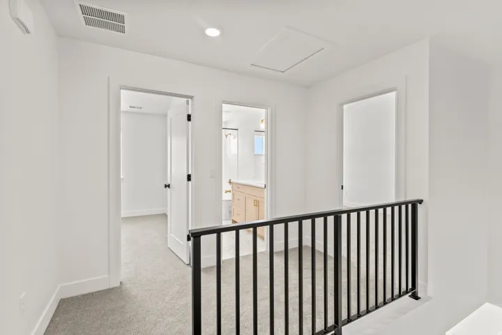 Open landing area featuring gray carpet and a black metal railing