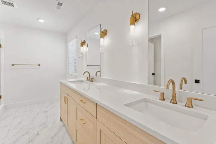 Double vanity with light wood-finish cabinetry, white countertop, and integrated sinks