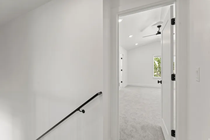 Vaulted ceiling, recessed lighting, ceiling fan, white paneled door, and dark hardware