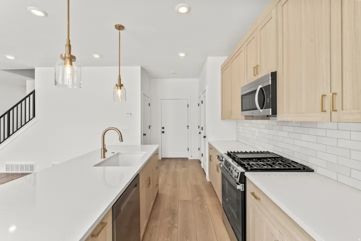 White kitchen island with undermount sink, brass finish faucet, and two pendant lights