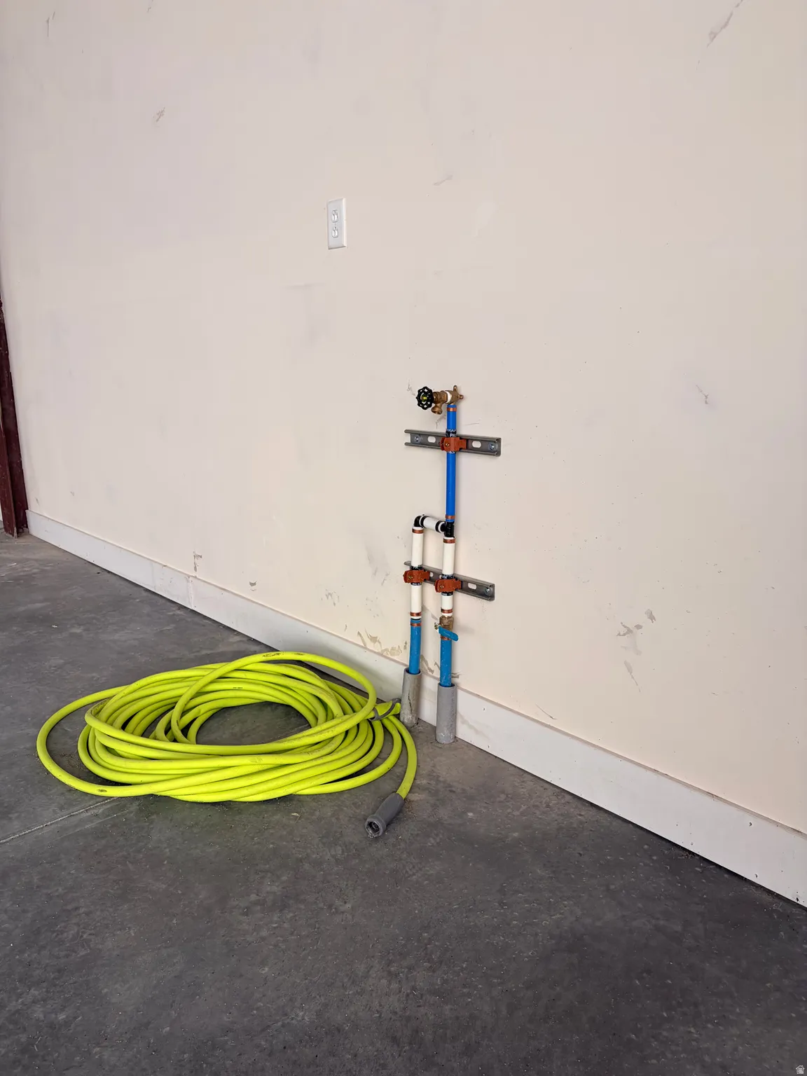 Utility wall with exposed plumbing, PEX piping, and a wall-mounted spigot