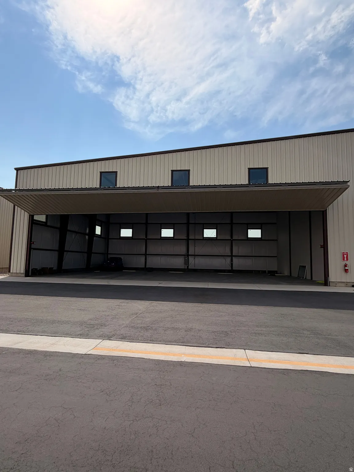 Industrial building with a large bi-fold hangar door, corrugated metal siding, and a paved approach