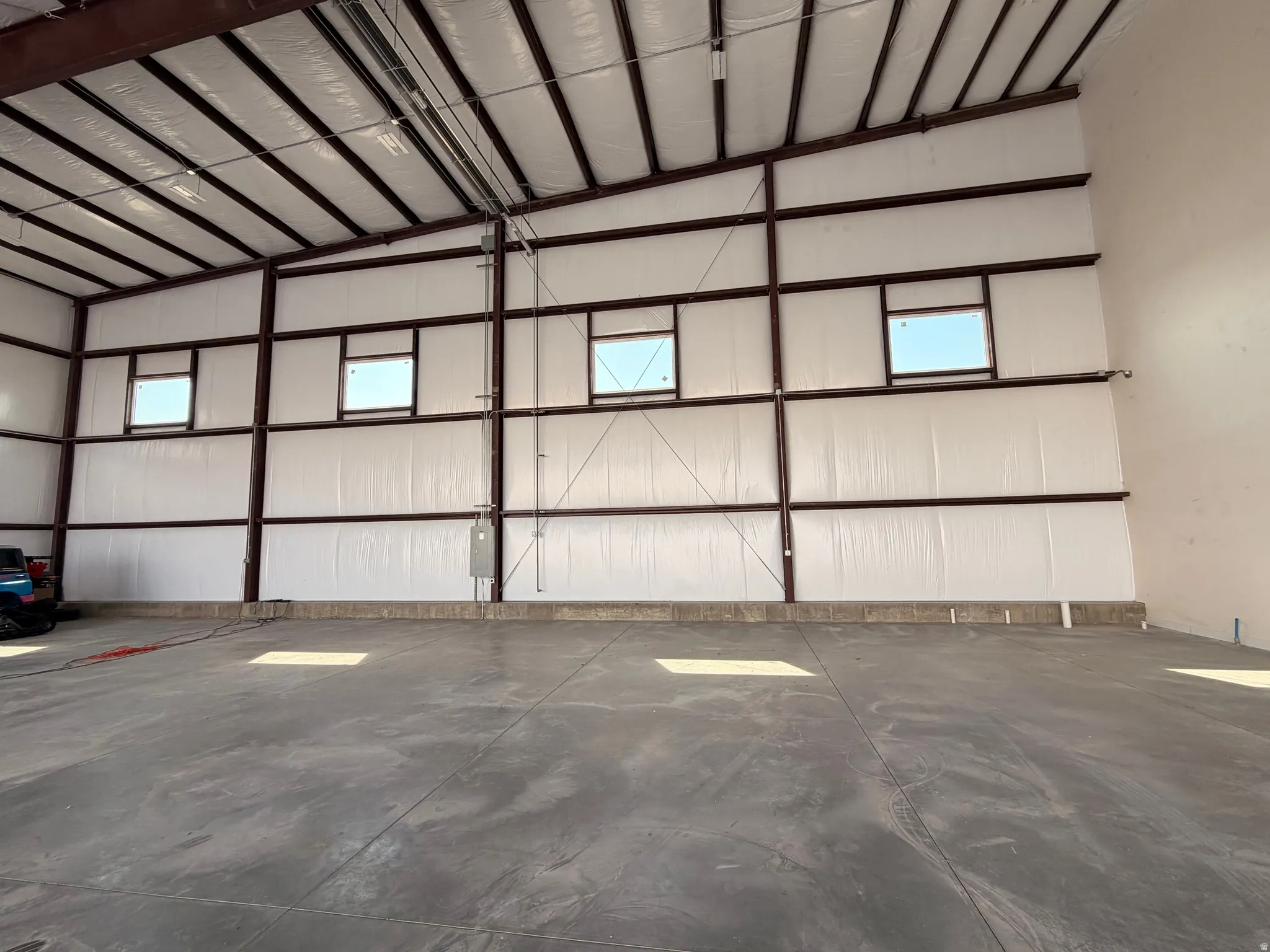 Expansive commercial interior featuring high ceilings with exposed steel beams, insulated paneling, and concrete flooring