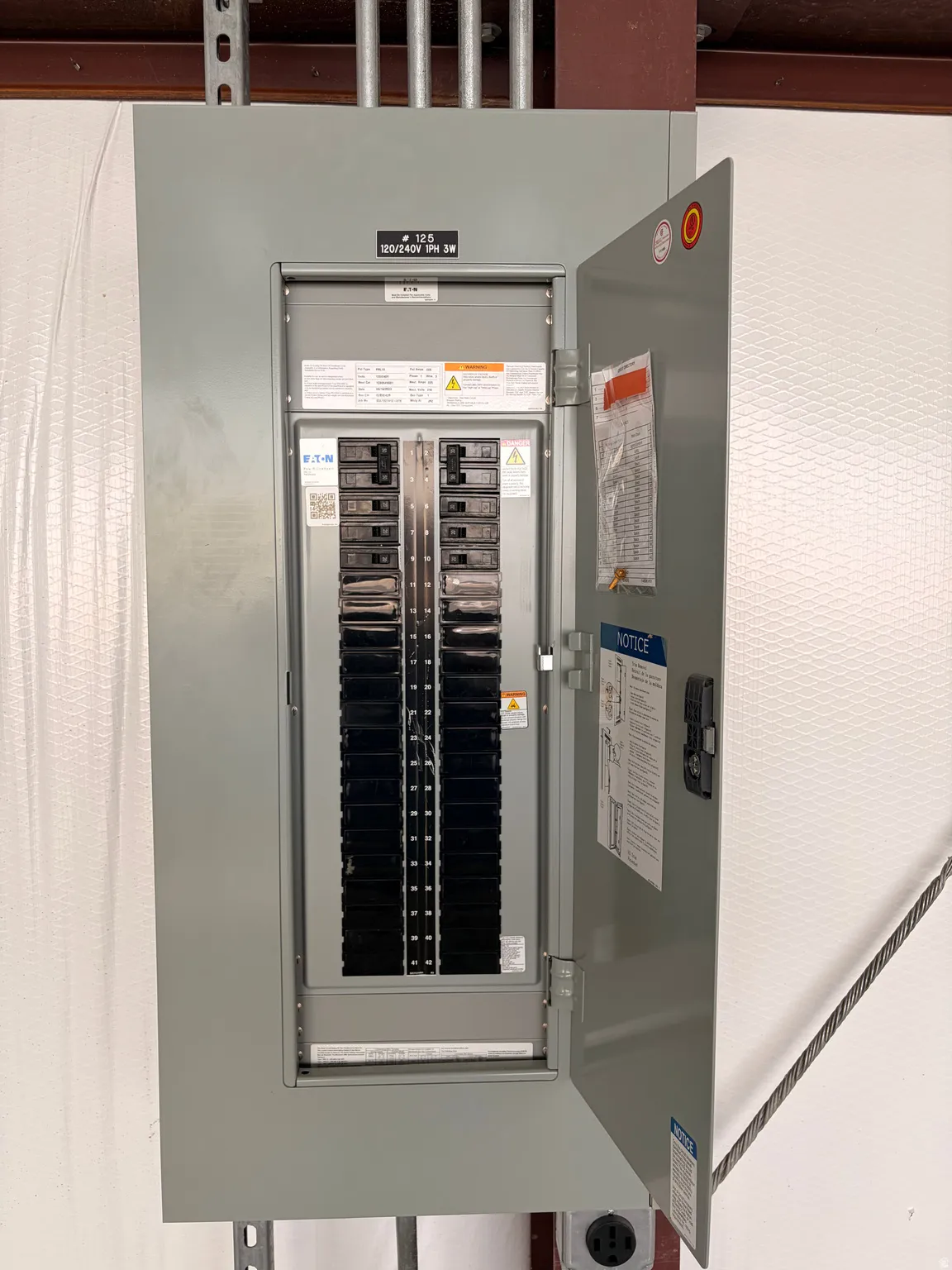 Electrical panel with a gray metal enclosure, hinged door, and visible circuit breakers