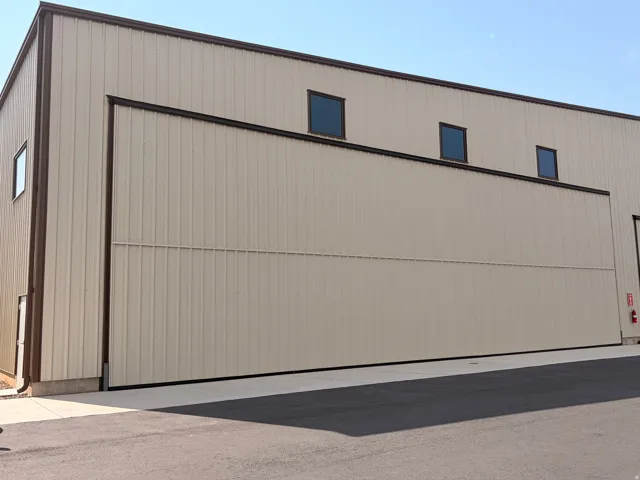 Corrugated metal building with a large sliding door, contrasting dark trim, and multiple high-set windows