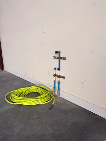Utility wall with exposed plumbing, PEX piping, and a wall-mounted spigot