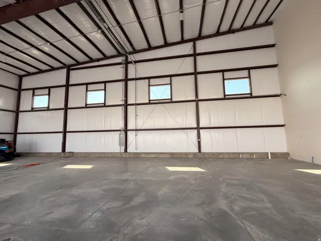 Expansive commercial interior featuring high ceilings with exposed steel beams, insulated paneling, and concrete flooring