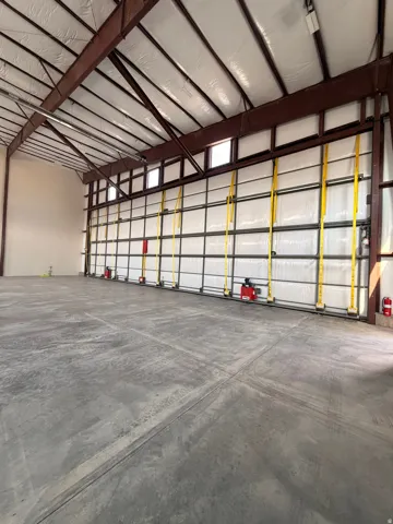 Spacious industrial interior featuring a high, insulated ceiling and exposed brown steel trusses