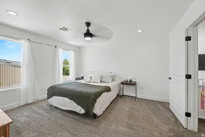 Room featuring two windows with white trim, recessed lighting, a ceiling fan with integrated lighting, and neutral carpeting
