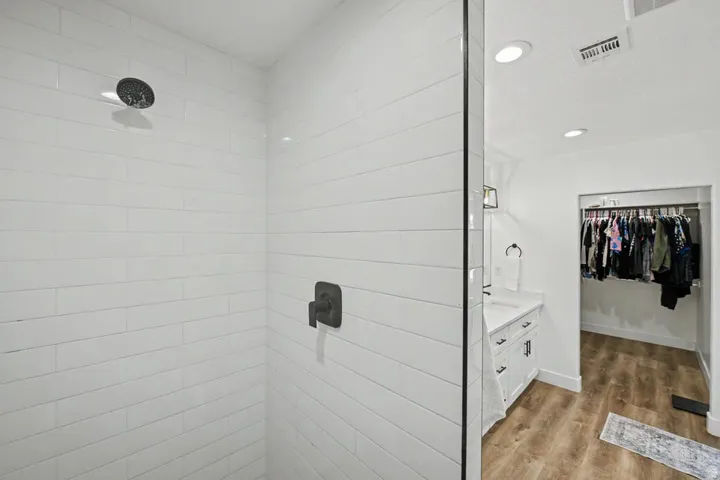 Glass-enclosed shower with matte black fixtures and horizontal white tile