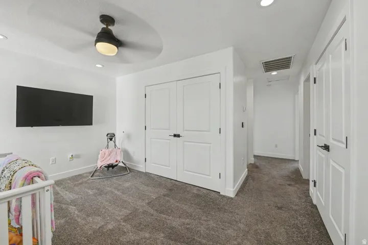 Recessed lighting, ceiling fan with integrated light, built-in closet with panel doors, dark-finish hardware, and wall-to-wall carpeting