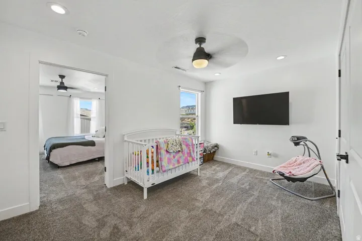 Carpeted room with recessed lighting, a ceiling fan, and a wall-mounted television