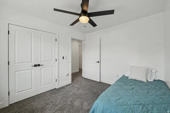 White walls, gray carpet, and a ceiling fan with integrated lighting