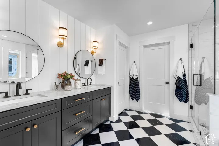 Dual vanity with dark cabinetry, white countertops, and circular mirrors