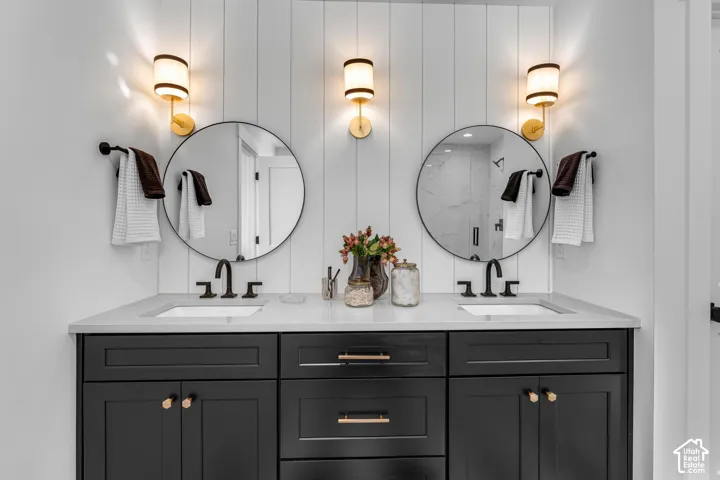 Double vanity with dark wood cabinetry, white countertop, and two round mirrors, each illuminated by a wall-mounted light fixture